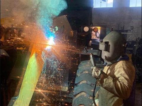 Soldador executando solda em componente de máquina pesada